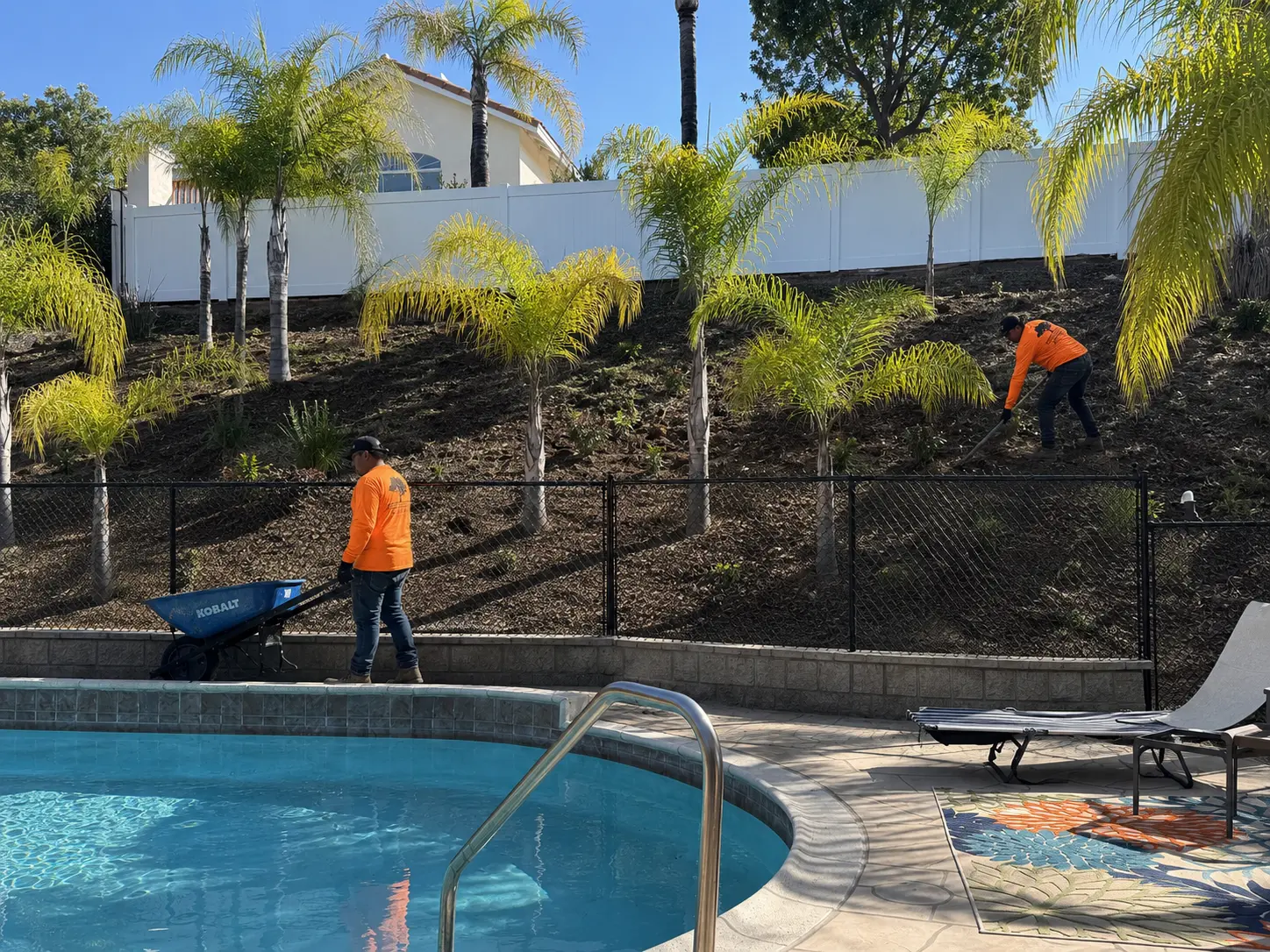 Robles crew maintaining a landscaped slope beside a residential pool